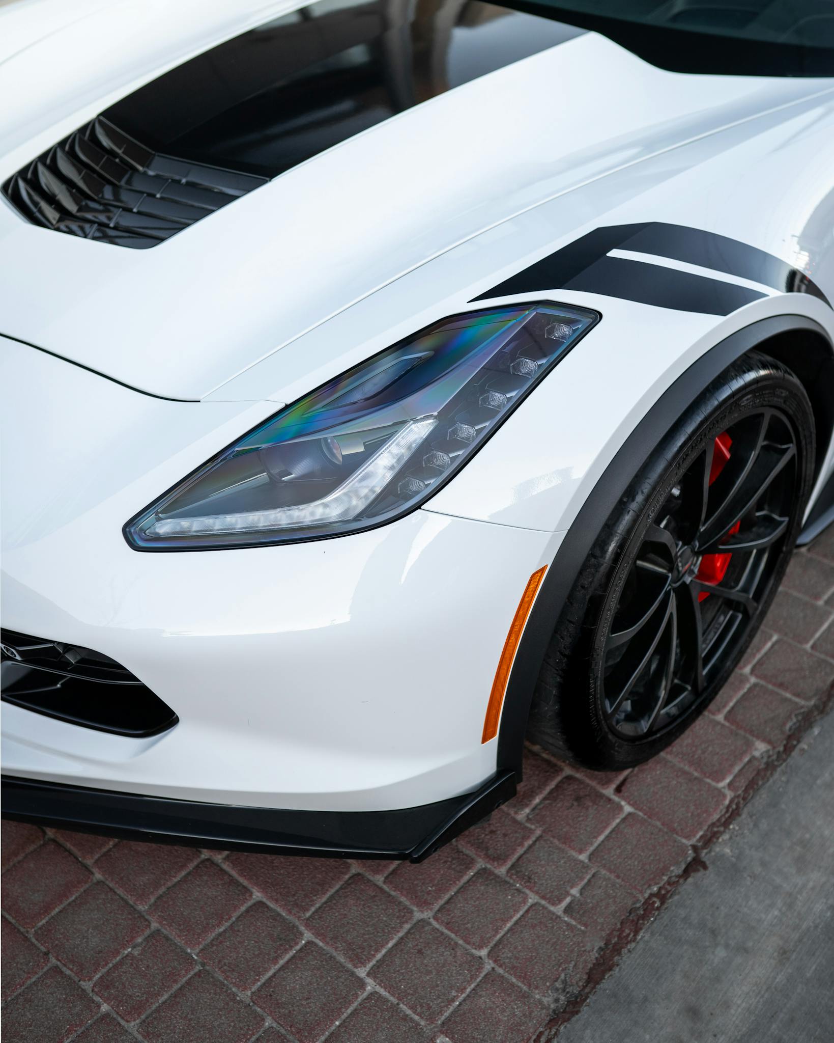 Detailed close-up of a white classic Corvette with polished chrome features and sporty design.
