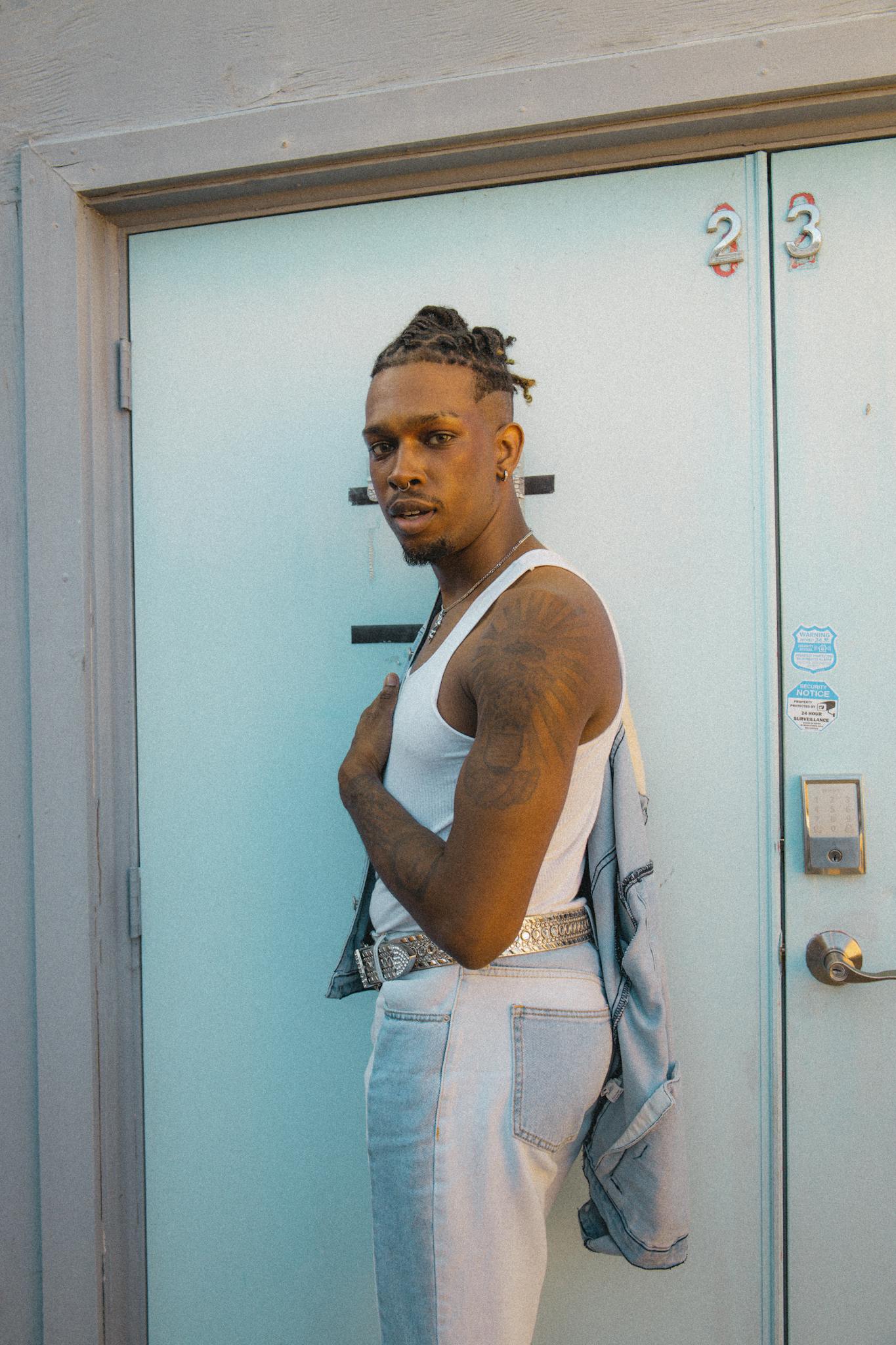 Stylish young man in casual attire posing confidently in front of a blue door.